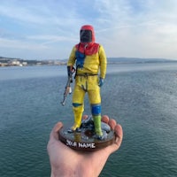 a hand holding a statue of a man in a yellow suit